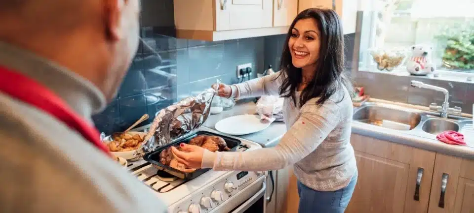 Woman happy cooking chicken on a stove