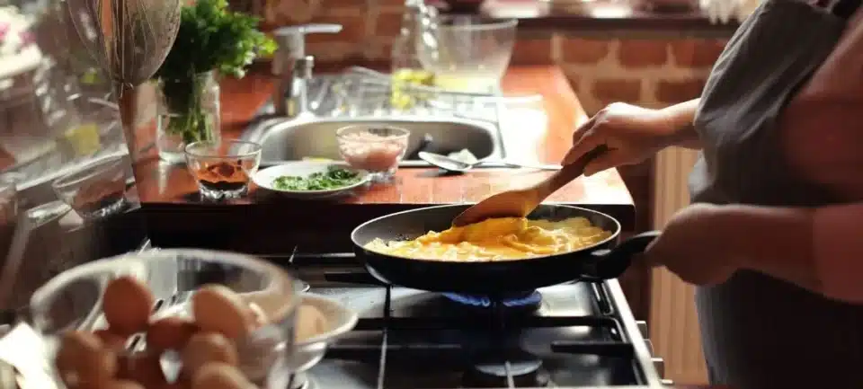 Lady cooking eggs on propane stove.