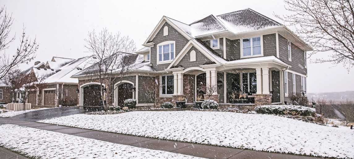Snow-covered two-story home and front lawn in winter